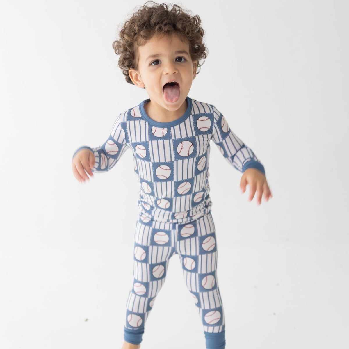 Child wearing a blue and white patterned pajamas featuring baseballs and stripes
