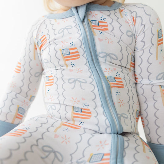 Baby wearing a onesie with flag pattern on a plain background