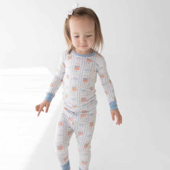 Child wearing American Flag PJs featuring blue accents and blue bows.