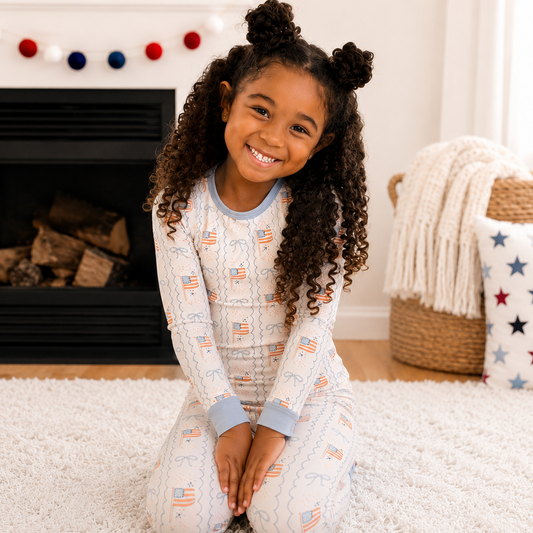 Young girl sitting on a carpeted floor wearing pajamas with American flag design.