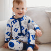 A baby in a blue and white Duke University themed romper with smiley face and logo patterns.
