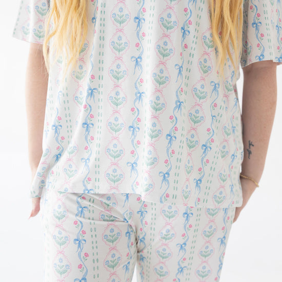Person wearing a white pajama set with blue and pink floral patterns on a plain background