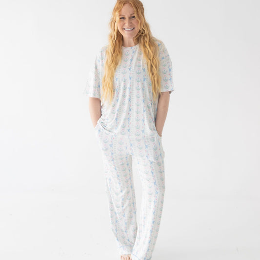 Woman wearing pajama set with a dainty blue floral with bows pattern on a white background