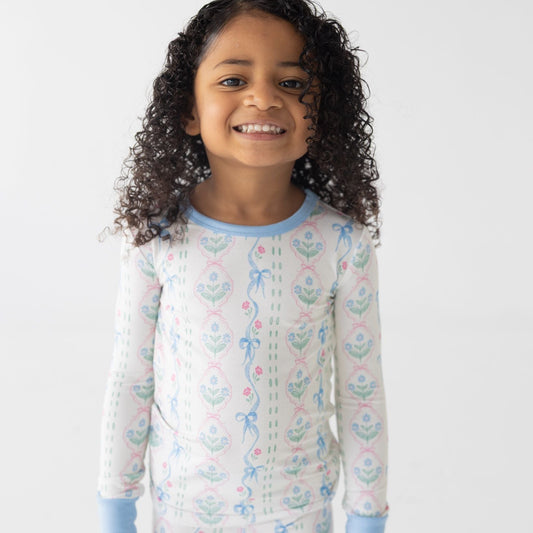 Child wearing a long-sleeve pajama with a dainty blue pattern on a white background