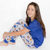Teenager wearing a blue shirt and Duke University pants featuring basket ball hoops, basket balls, Duke Banner, Stars. Sitting on a white background