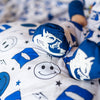 A baby in a blue and white Duke University themed romper with smiley face and logo patterns.