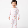 A toddler standing against a plain light gray studio background, wearing a long-sleeve pajama set with a white base and a repeating pink ice cream theme.