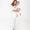 A woman holding a baby wearing matching white pajamas with a repeating brown puppy in a blue floaty print