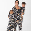 A woman and two children wearing matching black pajamas with black long-sleeved pajamas with dogs dressed up in costumes. 