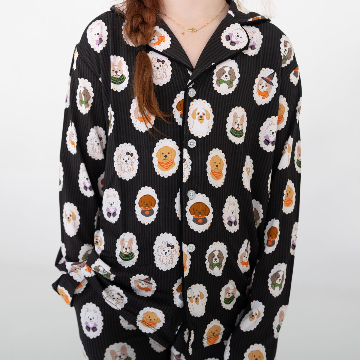 A person wearing a black long-sleeve two piece pajamas with dogs dressed up in costumes. 