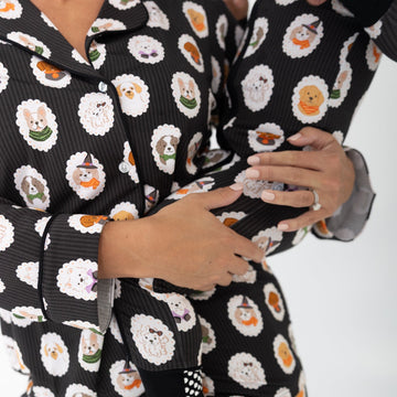 A close-up of a person wearing a matching black pajama set with a white, orange, and gray sushi print, hugging themselves against a plain white background.