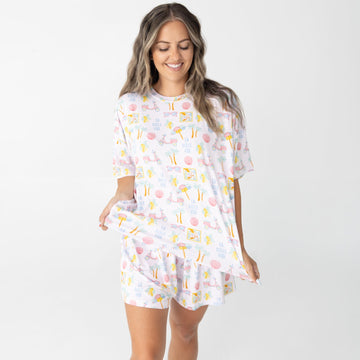 A woman modeling a matching short-sleeve t-shirt and shorts lounge set with a colorful ice cream cone pattern on a white background, set against a plain light gray studio backdrop.