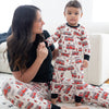 Woman and child wearing matching pajamas with fire truck pattern on a white couch.